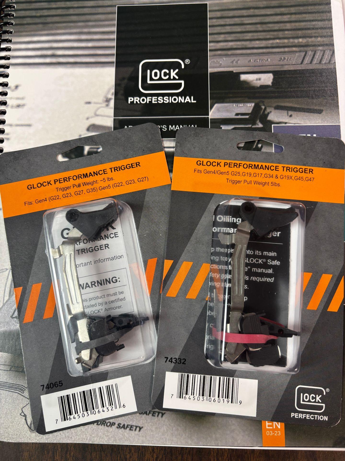 Two packaged Glock performance triggers on a Glock professional manual.